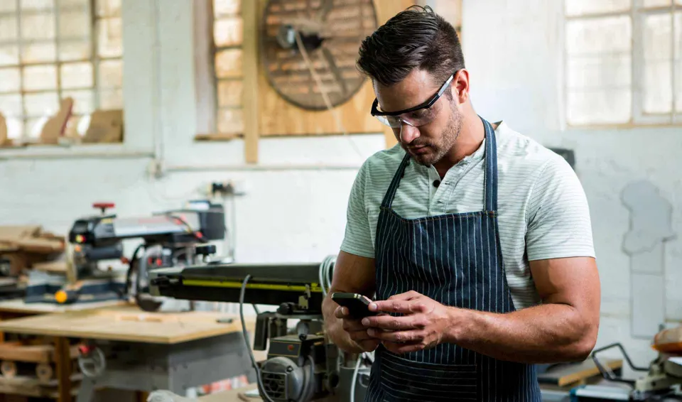 Medewerker stemt op zijn smartphone in de werkplaats
